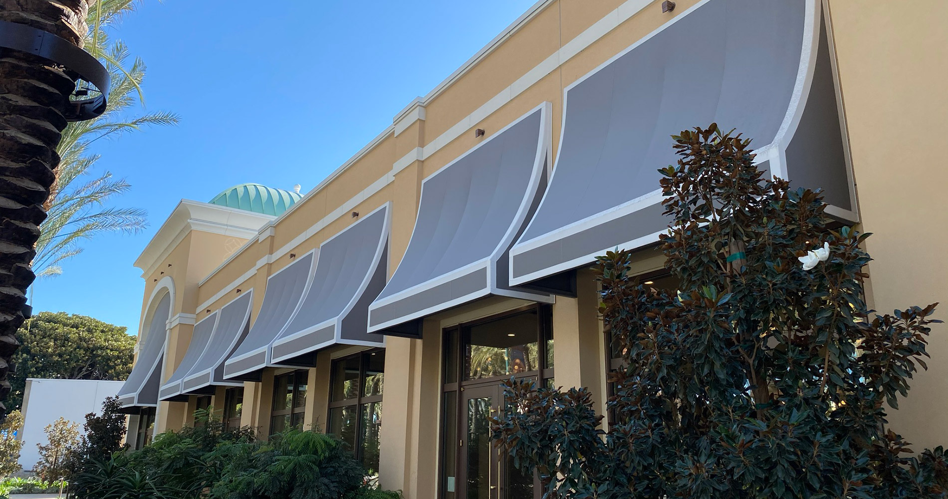 Building with large windows and gray awnings.
