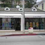 Calypso clothing store with window dress displays and potted plant.