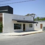 Single-story building with large windows and black awning.
