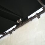 Retractable awning mechanism attached to cracked wall.