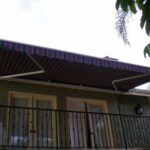 Retractable striped awning over balcony with metal railing.