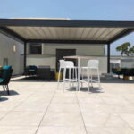 Modern rooftop patio with tables, chairs, and sofas under pergola.