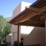Person standing under covered patio with wooden beams.