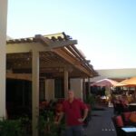 Man standing under wooden pergola.