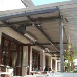 Restaurant patio with pergola, tables, and diners.