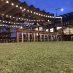 Outdoor dining area with string lights and wooden tables.