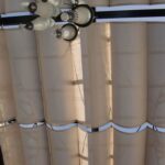Fabric shade panels on metal pergola with hanging chandelier.