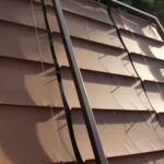 Metal roof with overlapping panels and support bars.