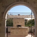 Outdoor kitchen with stone oven and counter under canopy.