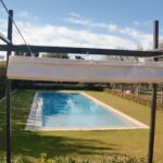 Outdoor swimming pool seen through metal pergola.