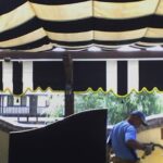 Two people working under a striped canopy.