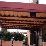 Patio with retractable awning, potted plants, and chairs.