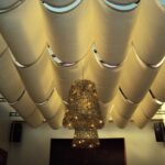 Wave-patterned fabric ceiling with woven hanging light fixture.