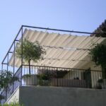 Balcony with metal frame, fabric canopy, potted plants, railing.