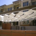 Fabric shade panels suspended in a wave pattern above courtyard.