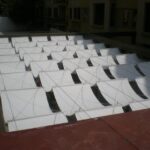 Shade sails in a grid above a courtyard, suspended by cables.