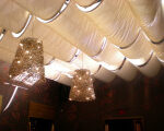 Three pendant lights hanging from draped ceiling fabric.