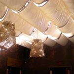 Two woven pendant lights hang from fabric-draped ceiling.