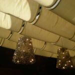 Metal pendant light fixtures hanging from folded ceiling panels.