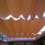 Fabric panels form a wave-patterned retractable shade over patio.