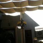 Metal chandelier beneath wavy fabric patio cover.