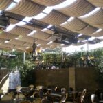 Patio tables and chairs beneath a wavy fabric canopy.