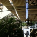 Person standing beneath canopy with chandeliers.