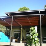 Patio with metal and polycarbonate roof, furniture covered with tarps.