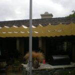 Backyard patio with scalloped canopy, furniture, grill, and umbrella.