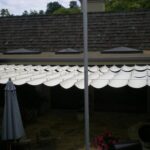 Retractable fabric patio shade extended over stone patio.