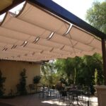 Covered patio with shade panels over outdoor tables and chairs.