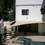 Person under shade sail near patio hot tub.
