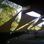 Triangular shade sails attached to a wooden structure.