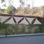 Modern building with geometric shade sails and ivy-covered wall.