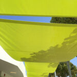 Fabric shades stretched above an outdoor walkway.