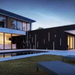 Modern two-story house with large windows and outdoor pool.