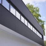 Modern building with black horizontal cladding and upper floor rectangular windows.