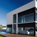 Modern two-story house with large windows and wooden deck.